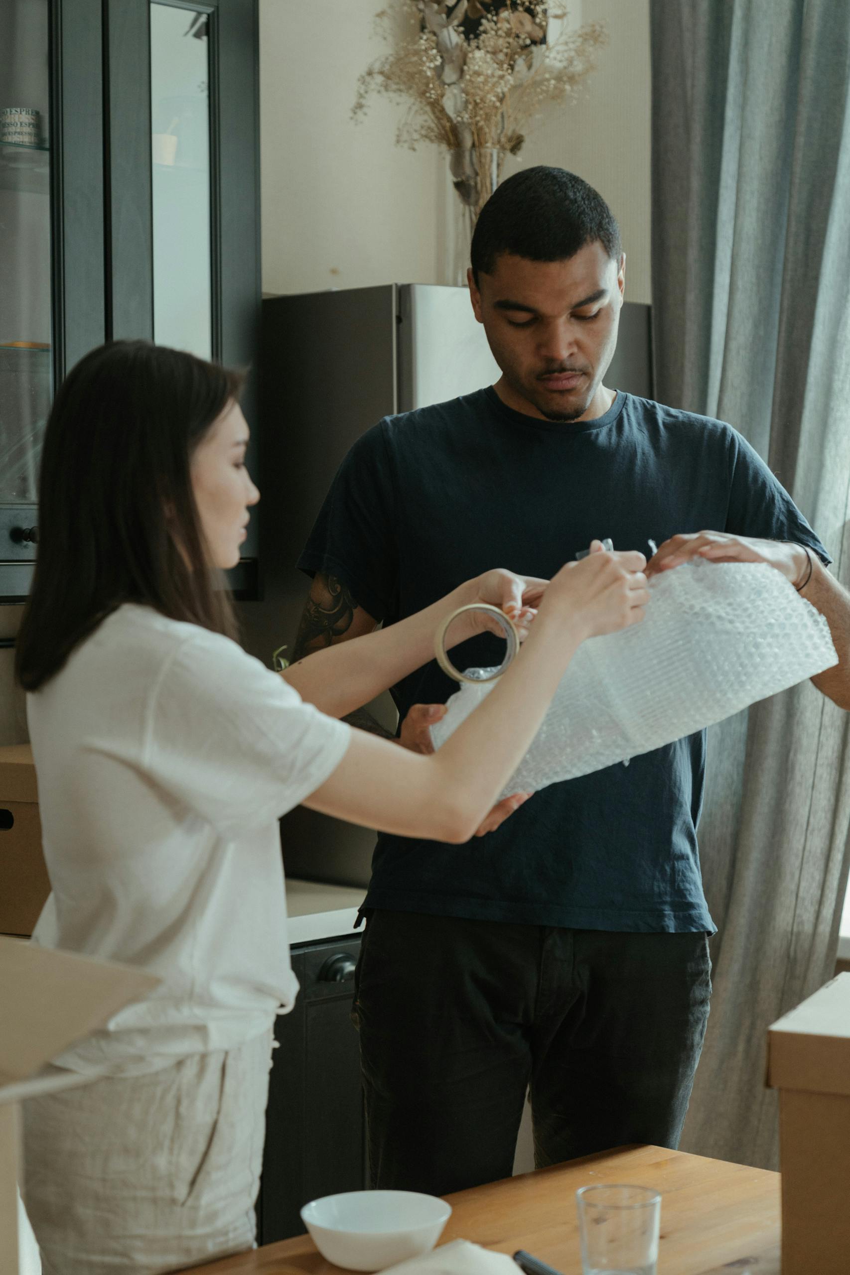 A couple in a new apartment carefully wrapping items with bubble wrap during a move-in.