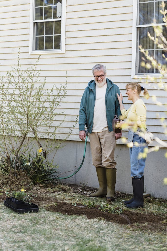 Elderly couple gardening outside their home with joy and happiness.